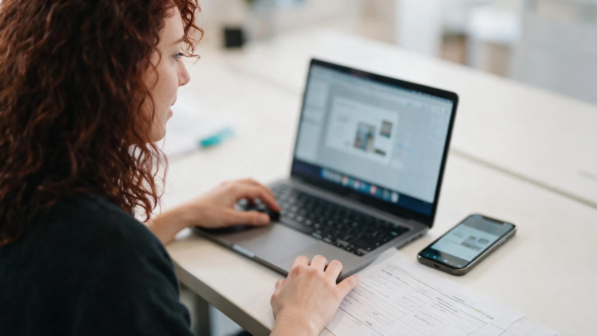 Woman working across a laptop and phone